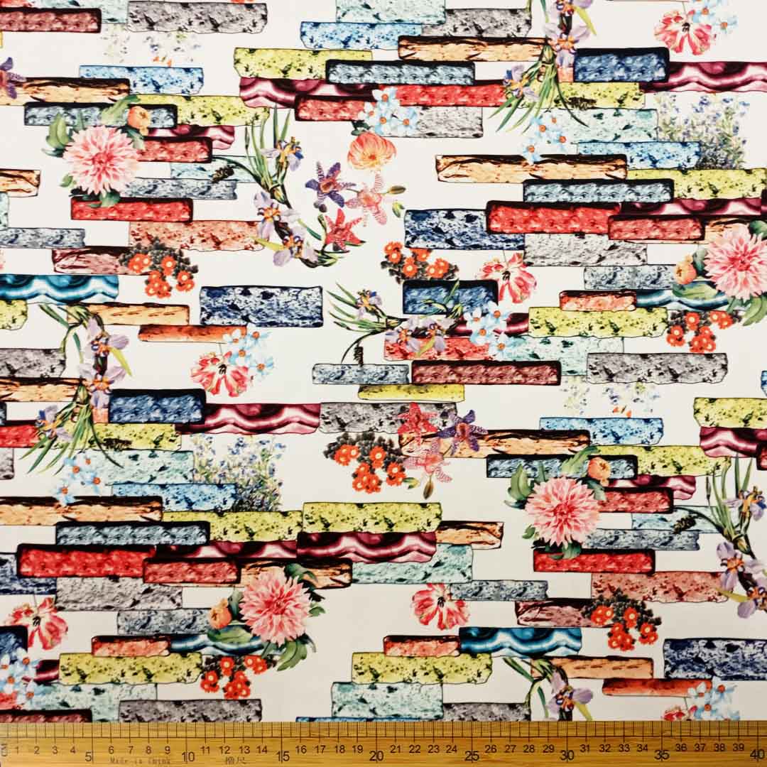 DR10996-08_1.jpg Scuba Digital Print fabric featuring a white brick pattern and floral prints, ideal for fashion, home décor, and upholstery projects.